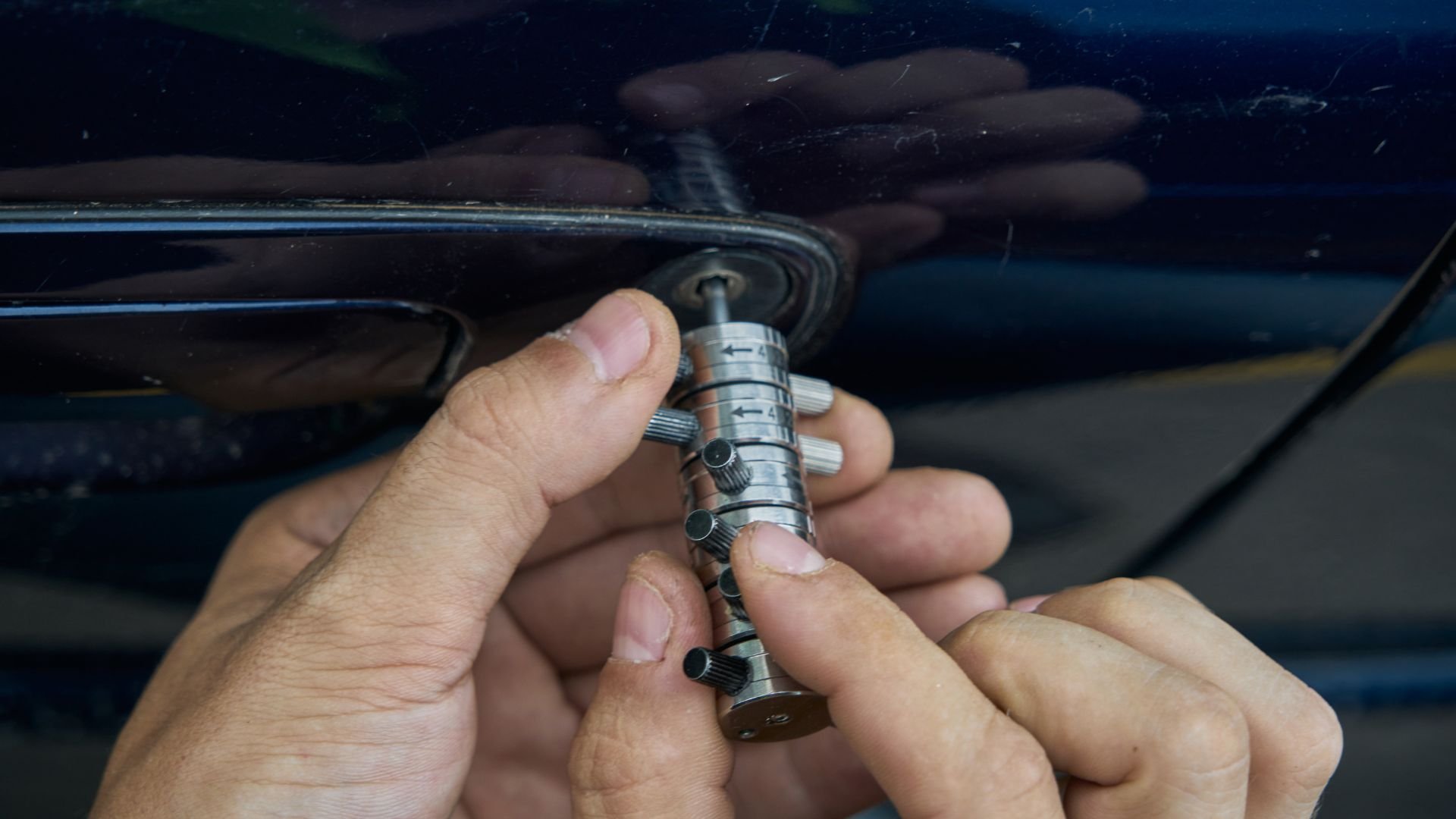 Hands adjusting a precise mechanical tool or instrument near a vehicle