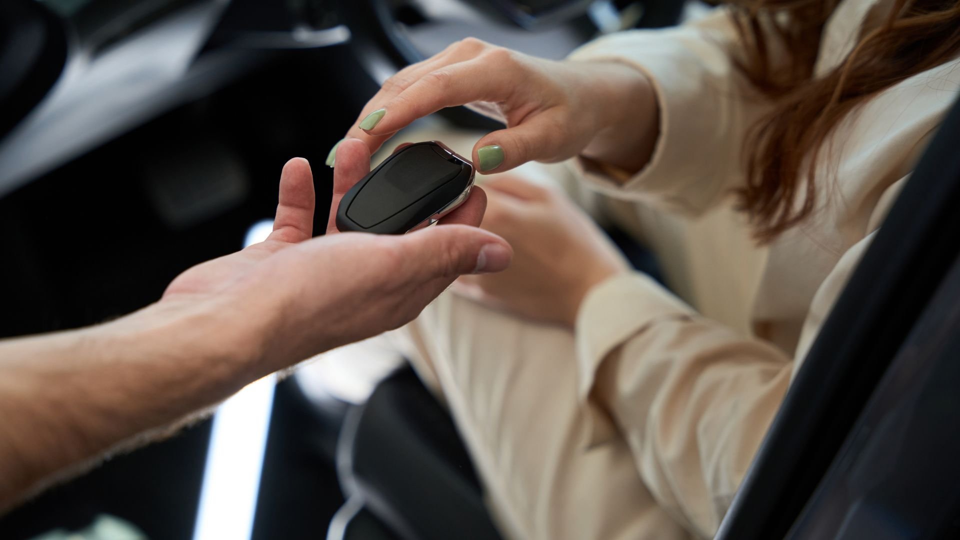 Hands exchanging a black smartwatch with green-painted nails