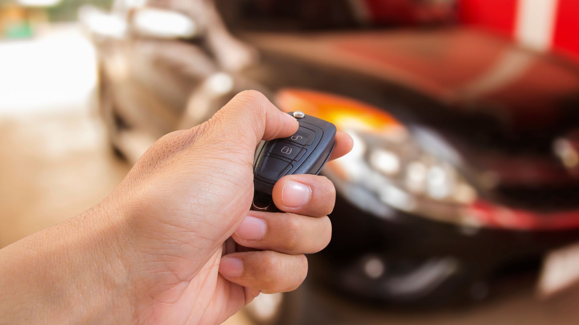 Hand holding car remote key with blurred car in background